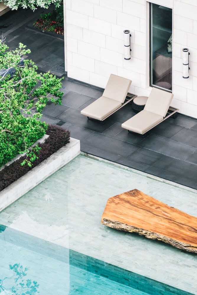 Turquoise pool beside stone paving and a pair of loungers