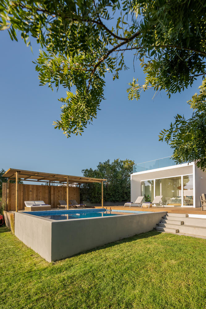 Pool beside a modern home with a timber pergola, lawn and garden